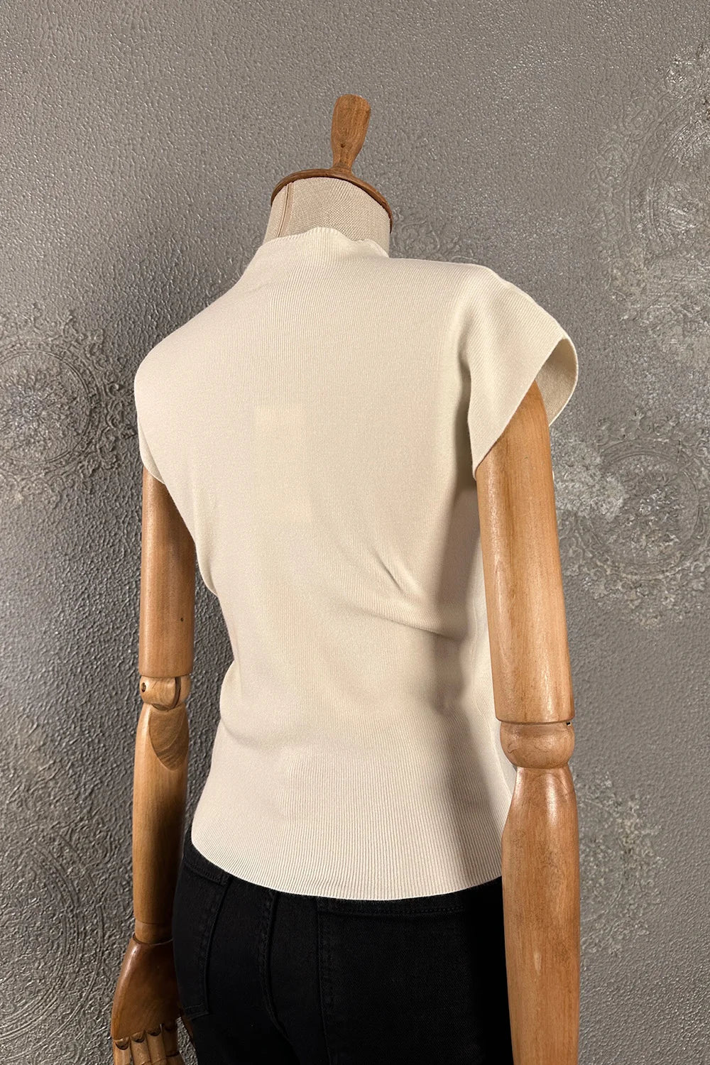 Krem dik yaka kolsuz triko, kadın ribli üst, dar kesim, yandan görünüm, şık ve minimalist tasarım