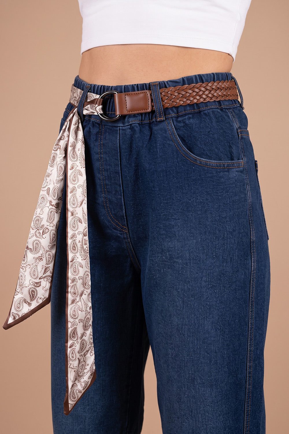 Lacivert barrel jean, kahverengi örgü kemer ve paisley desenli fular detaylı kadın pantolonu, önden görünüm.