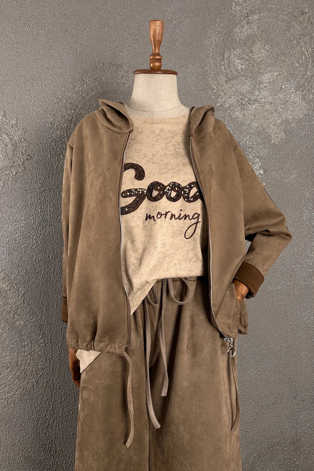 Bej nubuk eşofman takımı, kapüşonlu ceket ve bağcıklı pantolon, good morning yazılı tişört detaylı, kadın oversize kesim, önden görünüm.