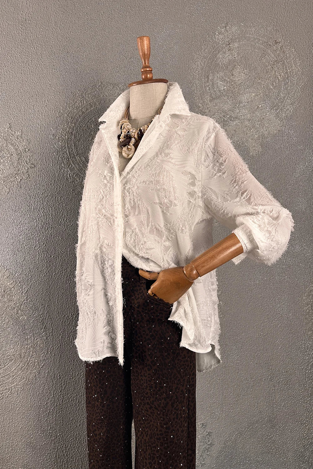 Beyaz dokulu oversize gömlek, siyah paçalı pantolon, kadın moda kombinasyonu, şal detaylı, yandan görünüm.