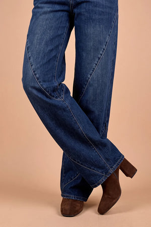 Koyu mavi geniş paçalı kadın jeans, kahverengi süet bot ile stilize, yandan detay görünüm