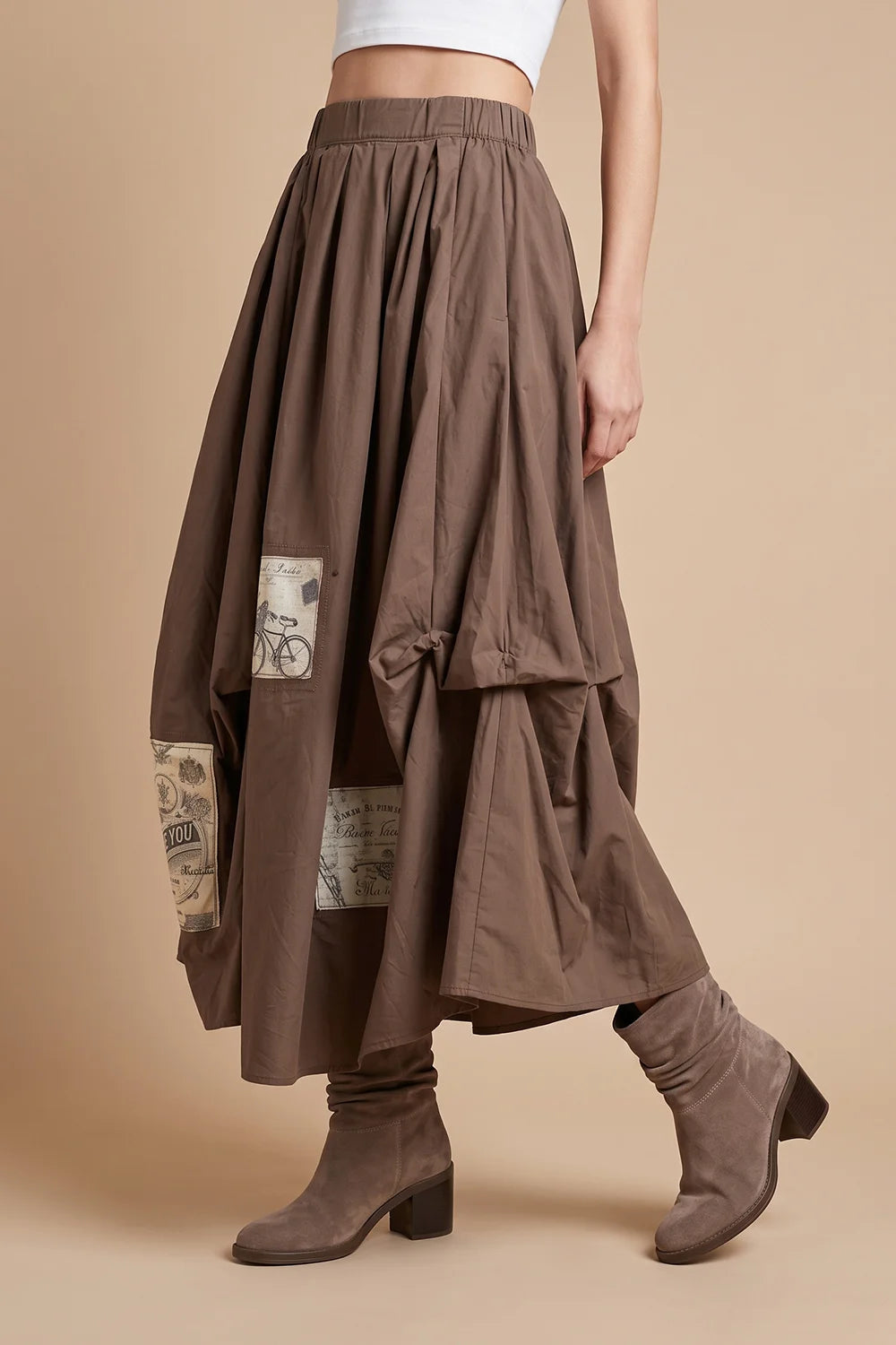 Kahverengi aplike detaylı maxi etek, elastik bel, geniş kesim, vintage desen, kadın moda, yandan görünüm.