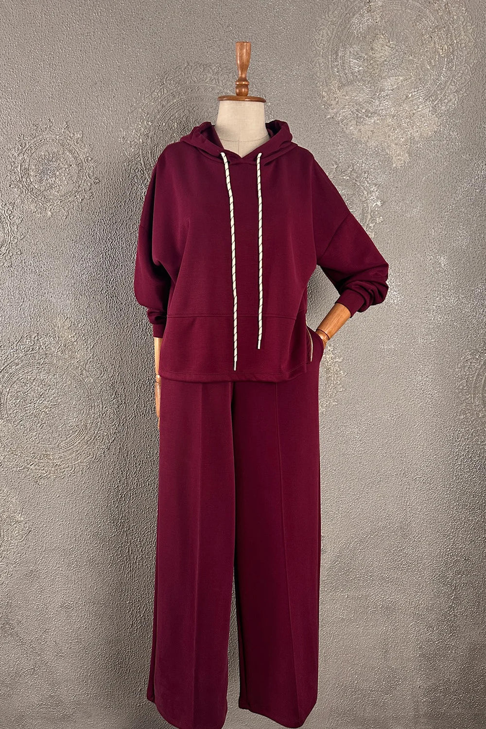 Bordo eşofman takımı, yumuşak dokulu, kapüşonlu hoodie ve geniş paça pantolon, kadın rahat spor giyim, önden görünüm.
