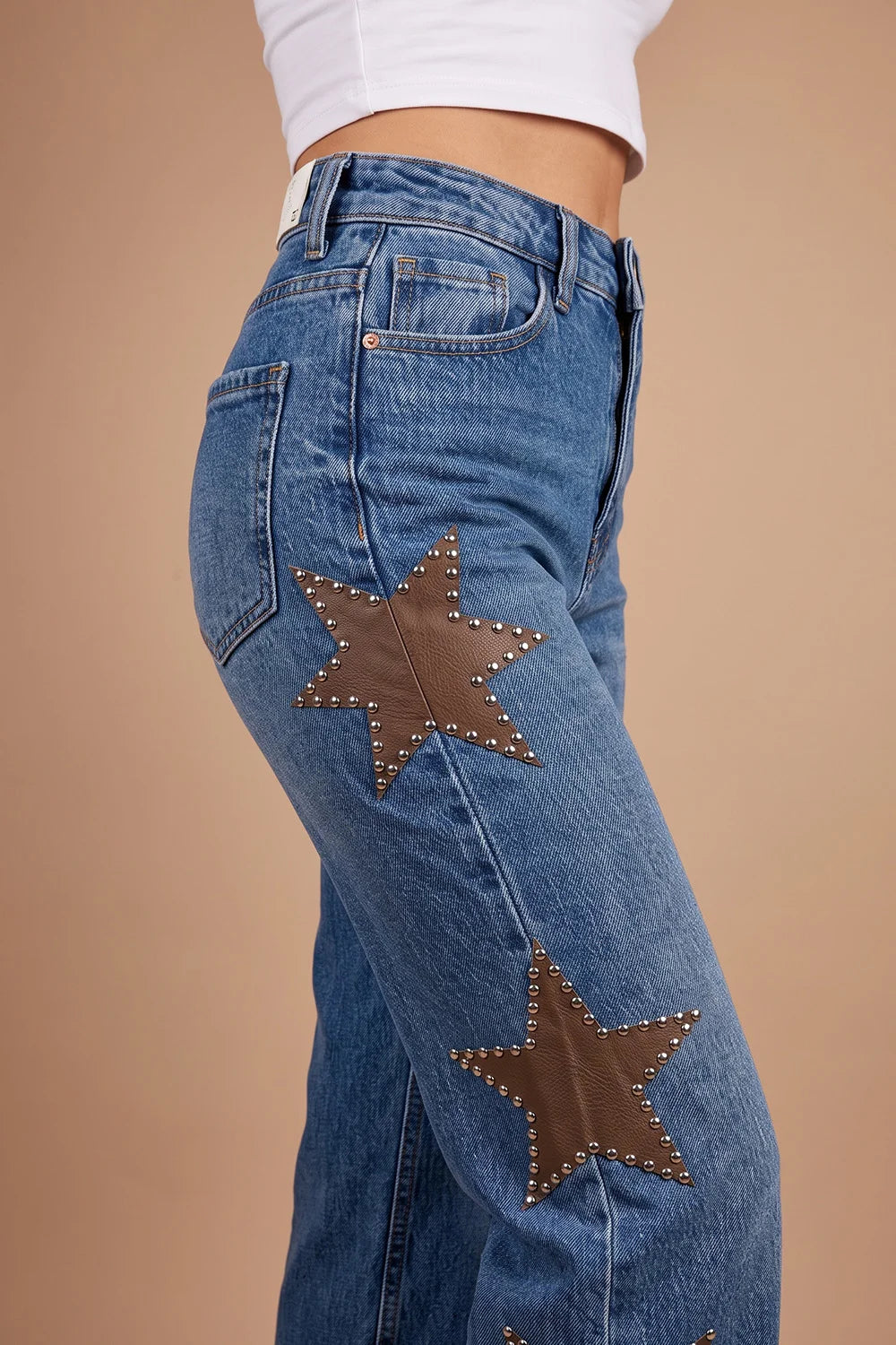 Mavi yıldız detaylı kadın jeans, kahverengi deri aplikeli, yüksek bel kesimi, yandan görünüm