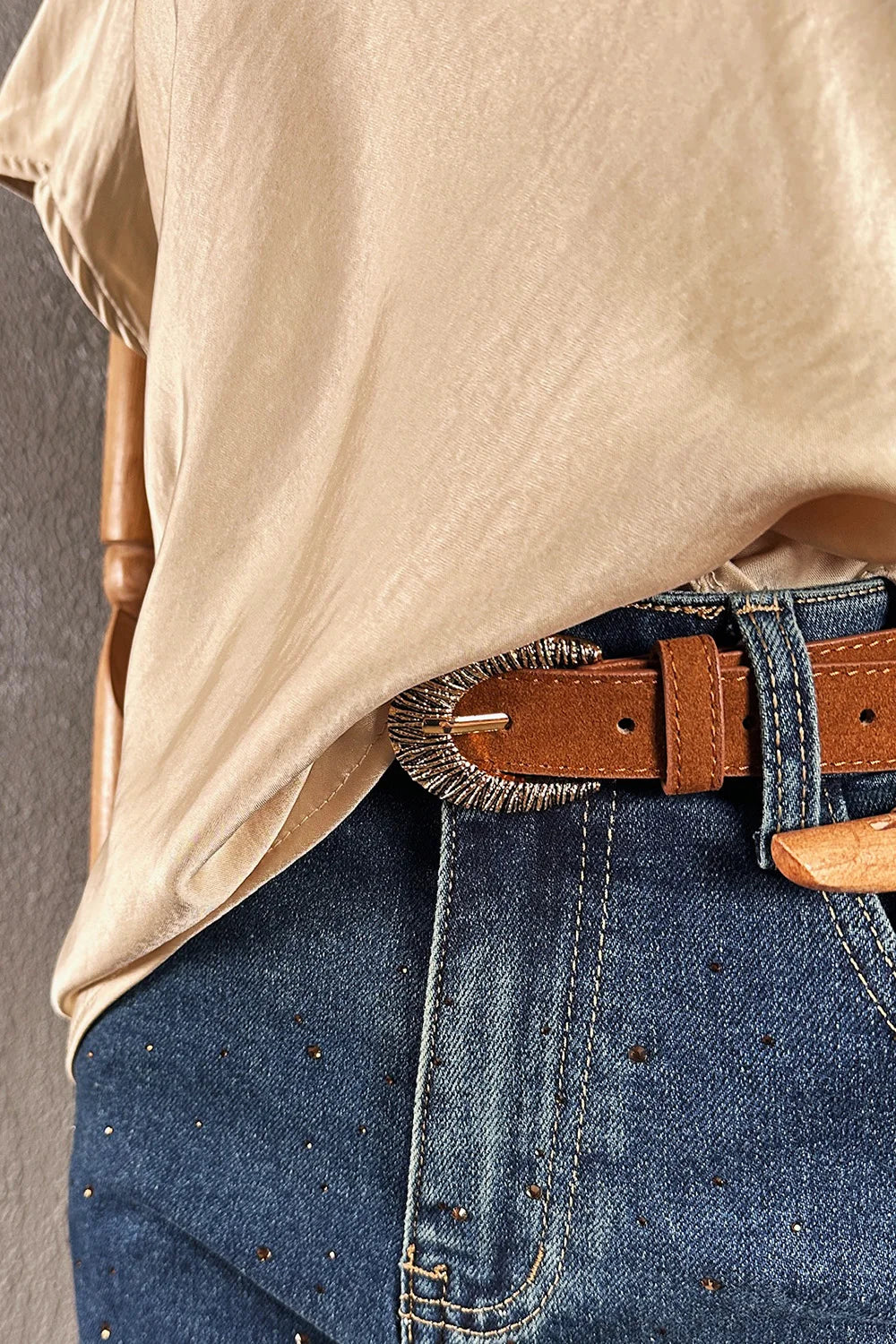 Krem saten kadın bluz, V yakalı kesim, denim pantolon ve kahverengi kemer kombinasyonu, önden görünüm