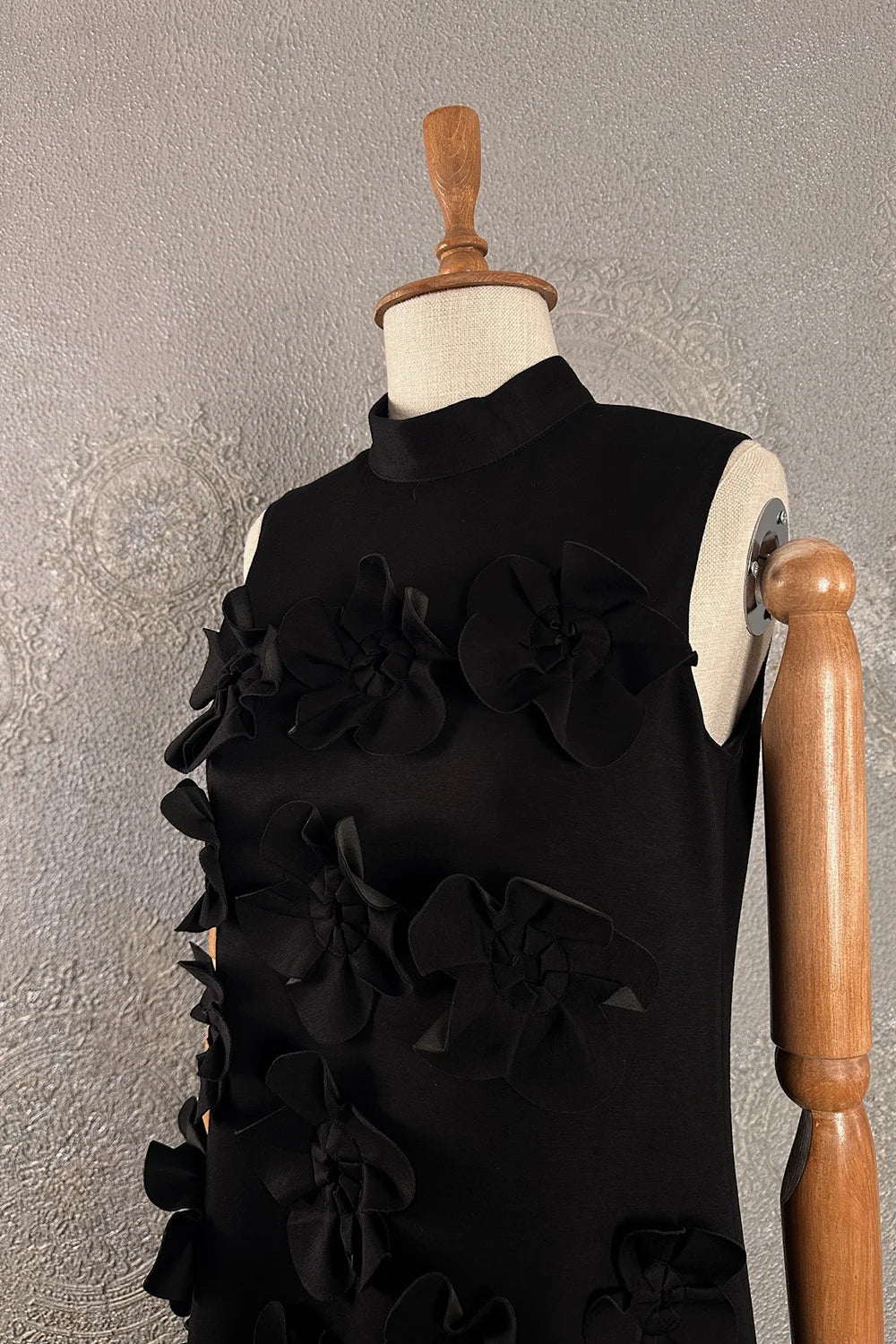 Siyah çiçek aplikeli midi elbise, kadın kolsuz tasarım, turtleneck yaka, önden görünüm, şık detay.