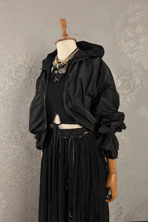 Siyah puffer ceket, hafif ve şık, kapüşonlu tasarım, ribli crop top ile kombinli, dantel detaylı etek, önden görünüm, kadın moda koleksiyonu.