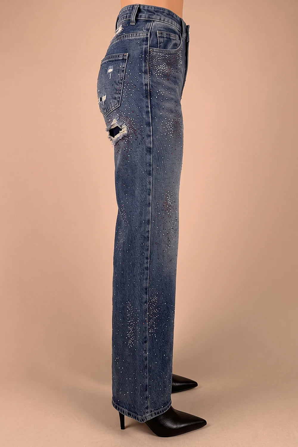 Taş işlemeli yırtık kadın jeans, koyu mavi denim, dar kesim, yandan görünüm, uzun paça