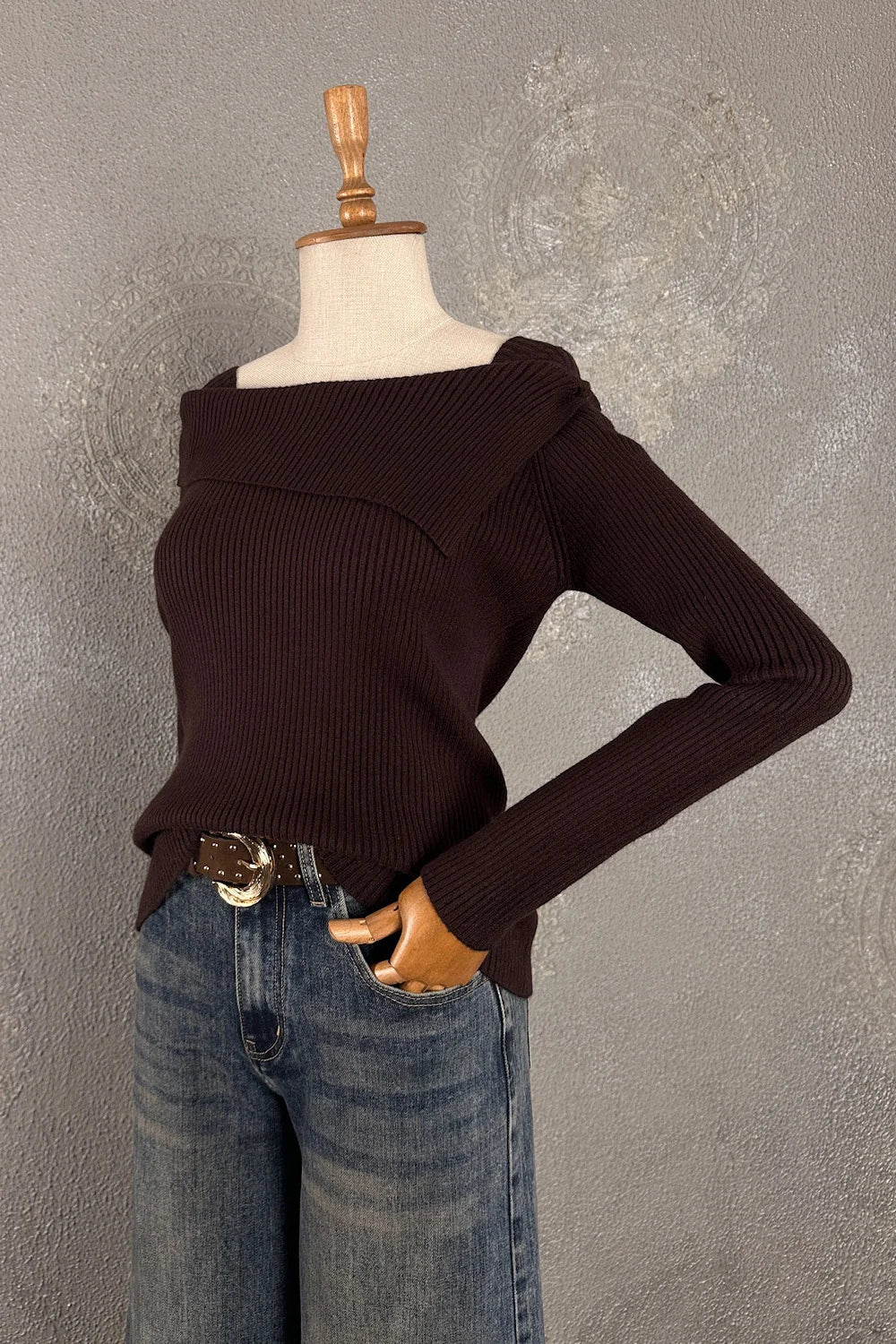 Siyah ribanalı triko, kadın off-shoulder kesim, uzun kollu, denim pantolon ile kombinli, stilize manken üzerinde görünüm.