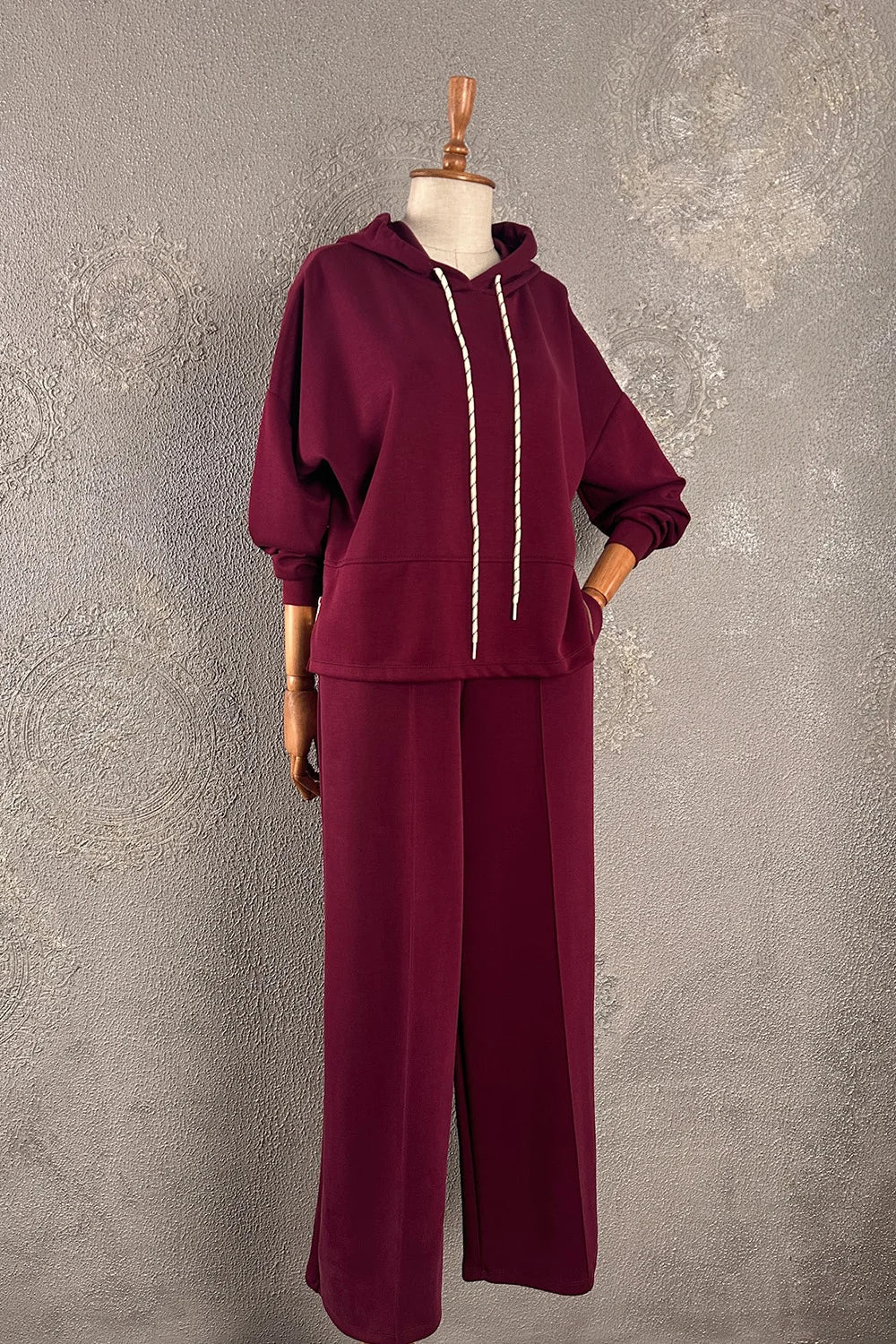 Bordo eşofman takımı, yumuşak dokulu, kapüşonlu hoodie ve geniş paça pantolon, kadın rahat kesim, önden görünüm.
