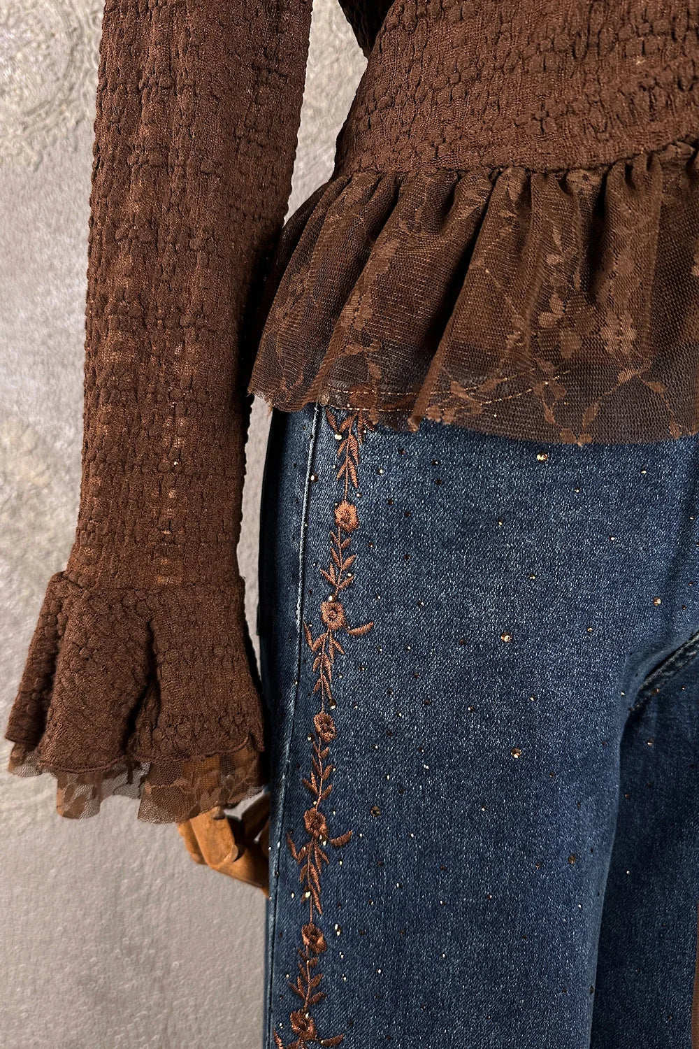 Kahverengi dantel volanlı kadın bluz, mavi denim pantolon kombinli, çiçek işlemeli detay, yandan görünüm