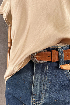 Krem saten kadın bluz, V yakalı kesim, denim pantolon ve kahverengi kemer kombinasyonu, önden görünüm
