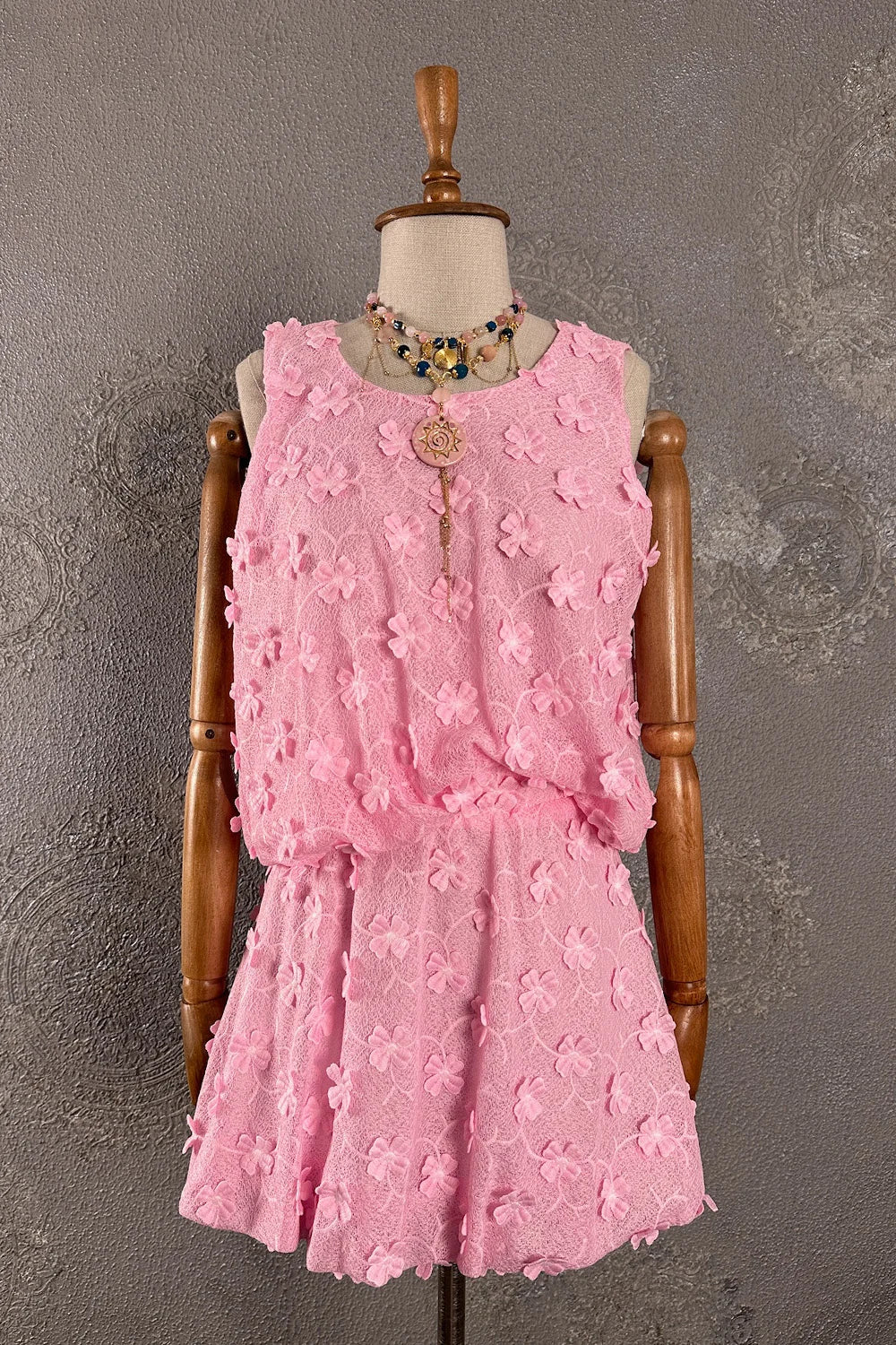 Pembe renk çiçekli etek takım, dokulu kumaş, kolsuz kesim, ön görünüm, dekoratif aplike detaylı.