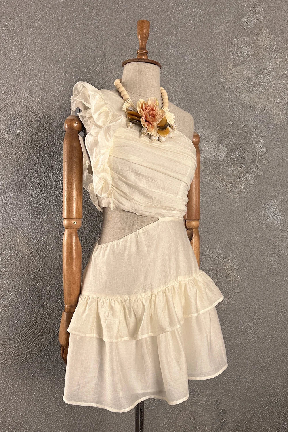 Krem renk tek omuzlu kısa elbise, buruşturmeli kumaş, çiçek detaylı, volanlı etek, yan kesim detayı